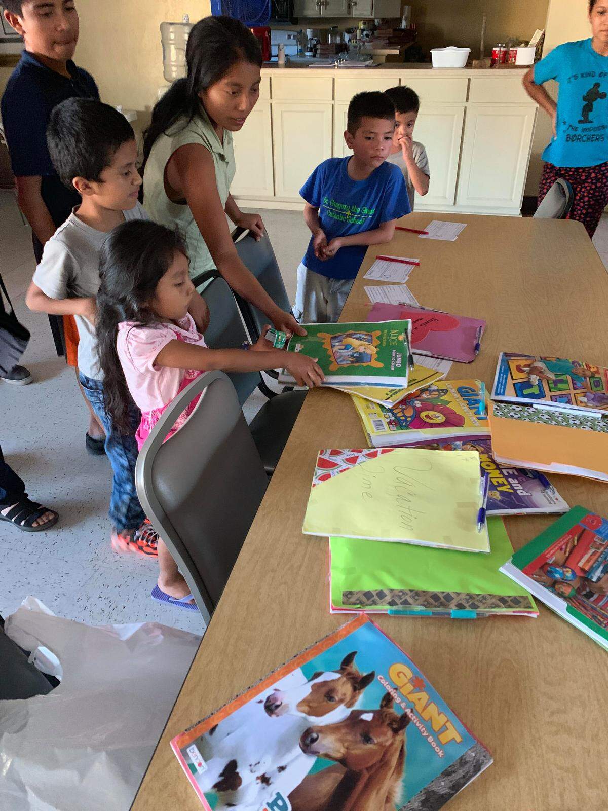 Children of immigrant families at a shelter in Texas pick out activity books made by Loredo resident Caridad Sarabia Ramos Cisneros.
