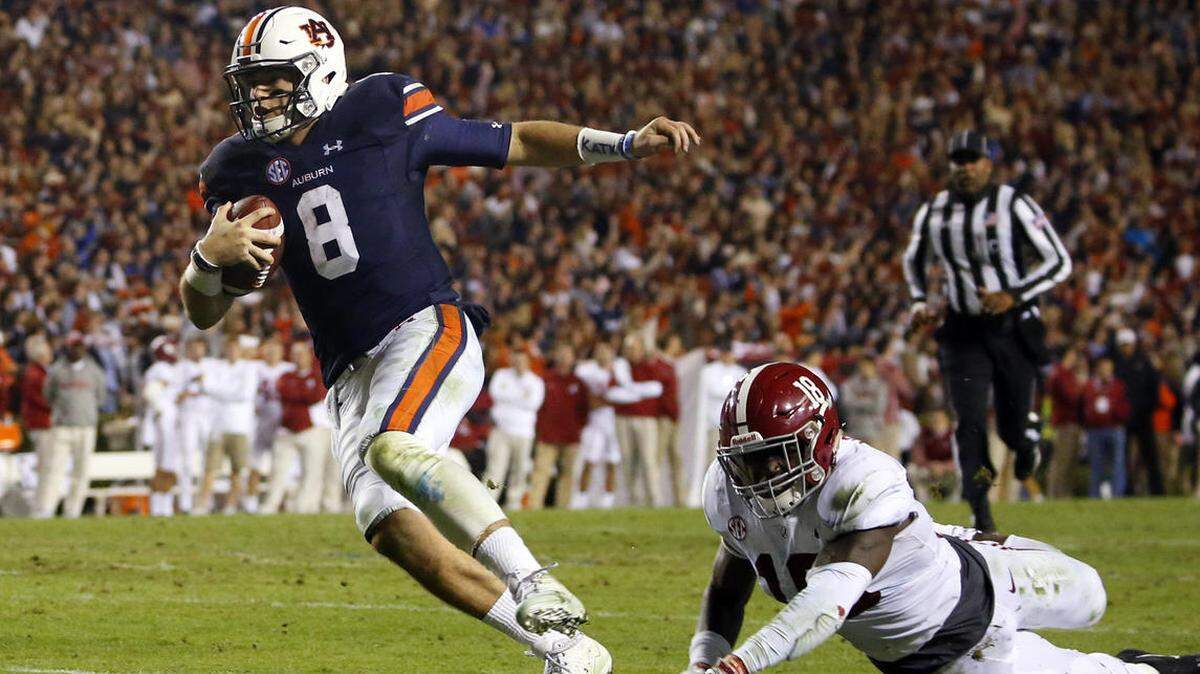 In this file photo, Auburn quarterback Jarrett Stidham (8) gets past Alabama linebacker Dylan Moses (18) to carry the ball in for a touchdown during the second half of the Iron Bowl NCAA college football game, Saturday, Nov. 25, 2017, in Auburn, Ala.