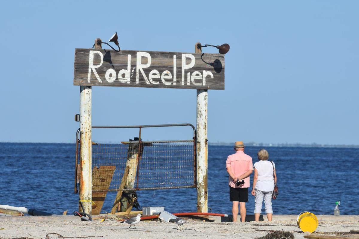Two people inspect the ruins of the Rod & Reel Pier on Anna Maria Island after Hurricane Milton.