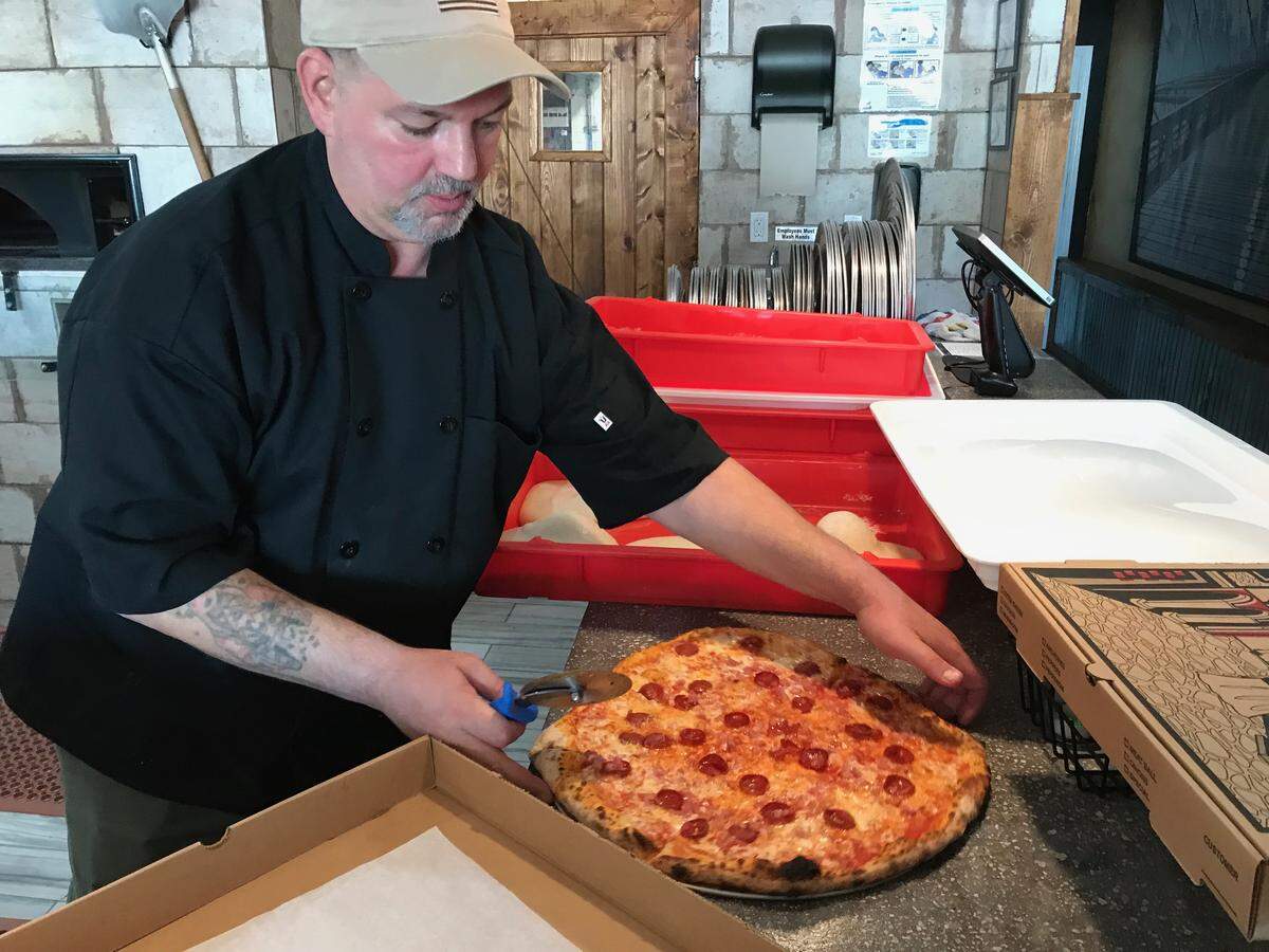 Alex Christianson prepares to cut a large pie for serving at Brancato’s Brick Oven Pizza, 5227 Manatee Ave. W., Bradenton.