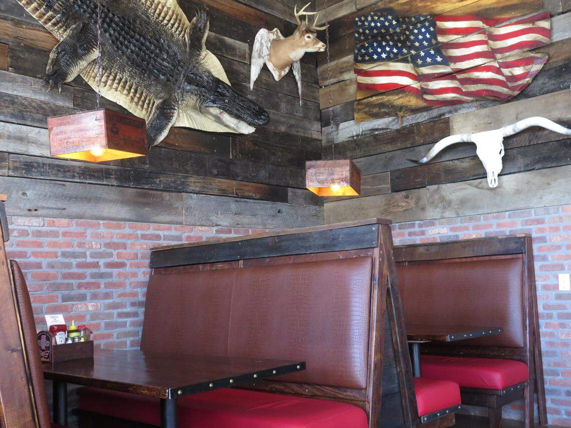 A host of southern Florida decorations line the walls at BoneYard BBQ, creating a different kind of Florida Everglades-inspired atmosphere. Pictured here are wooden-paneled walls, a mounted deer head, a longhorn skull and a mock alligator skin.