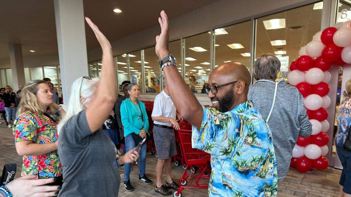 Store captain Abe’ Desta, right, high fives a customer Thursday, 10/26/2023, at the opening of Manatee County’s first Trader Joe’s at 8111 Cooper Creek Blvd. There were an estimated 300 people lined up for the store opening at 8 a.m.