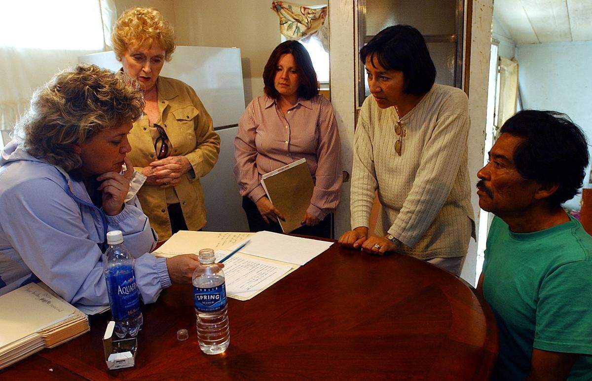 BRADENTON, 12/30/03--Cheri Coryea of Manatee County Community Services, County Commissioner Pat Glass, Lucy De La Cruz of the Homeless Coalition and Luz Corcuera of the Healthy Start Coalition meet with Trail Mobile Home Park resident Leonide Rivera in an attempt to provide him and his family with all the services he may qualify for.--photo by Tiffany Tompkins/d