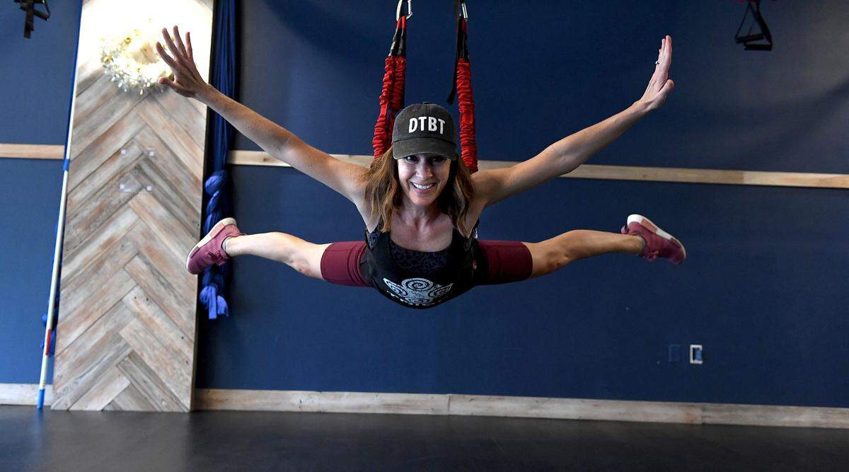 Jessica Currin, owner of One Tribe Fitness in downtown Bradenton, demonstrates exercises in a bungee harness.