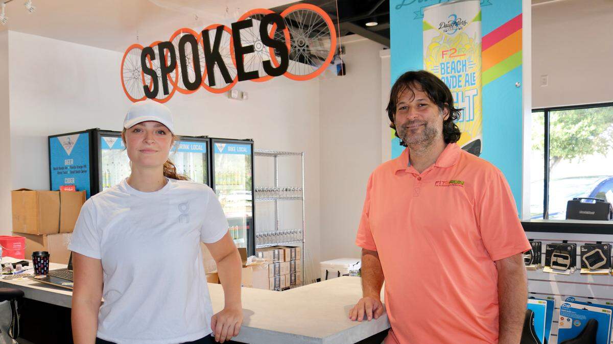 11/19/2021--Parks Robinson, president of Fit2Run, is shown with store manager Kendra Hopper at the company’s new flagship store at 4951 Cortez Road W., Bradenton. They are standing in front of the Spokes Bar, an innovation unique in the company to the new store.