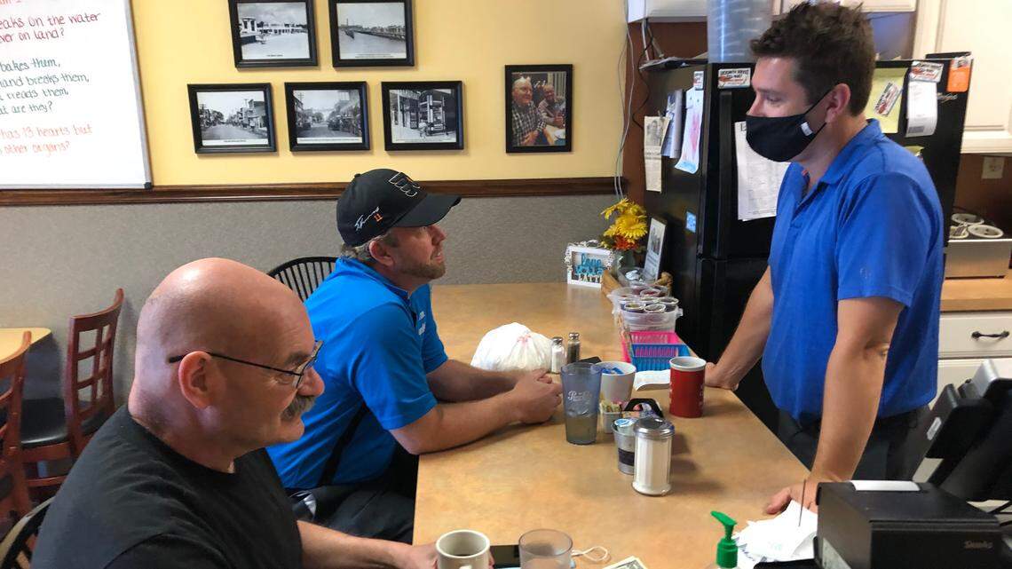 Rick Jesop, right, of Katy’s Cafe, 3130 53rd Ave. E., talks to customers just before closing Friday about the governor’s lifting of restrictions on restaurants.