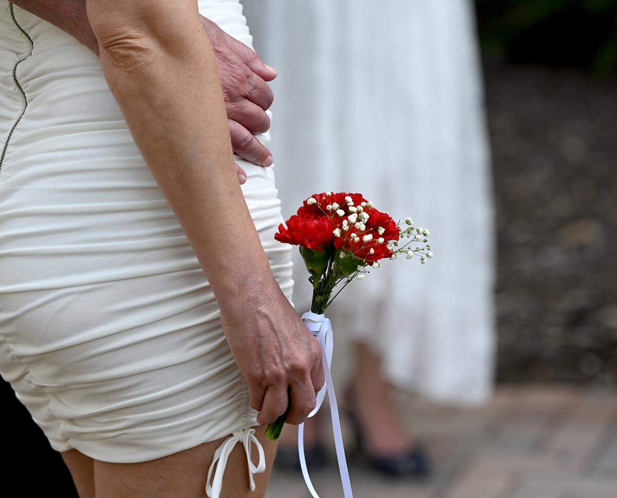 One bride holds a small bouquet at the Fifth Annual Valentine’s Day Group Wedding.