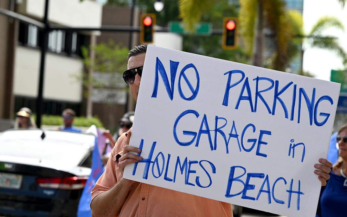 Ben Bryant holds a sign protesting a parking garage with other demonstrators in downtown Bradenton Friday. Gov. Ron DeSantis signed a law Friday that allows Manatee County to build Anna Maria Island beach parking garage despite protests from residents.