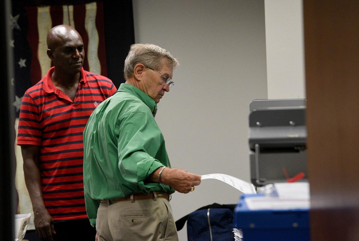 Manatee County Supervisor of Elections Mike Bennett feeds ballots into a tabulation machine Wednesday as the recount continues. One of the two tabulation machines was out of order, though the one continued the count as a repairman was called.