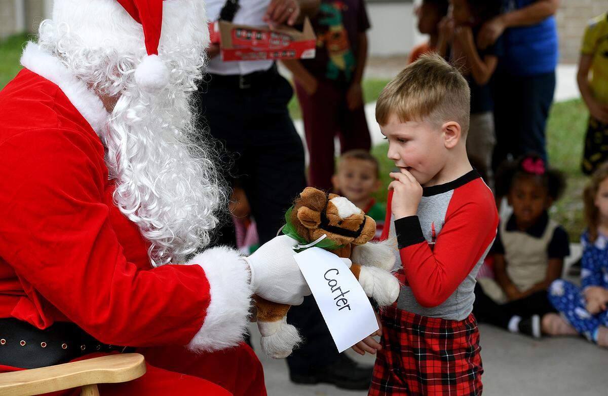 12/20/21—Carter Sullivan gets a stuffed horse from Santa, who arrived on an East Manatee Fire Rescue truck at Bashaw Elementary School.