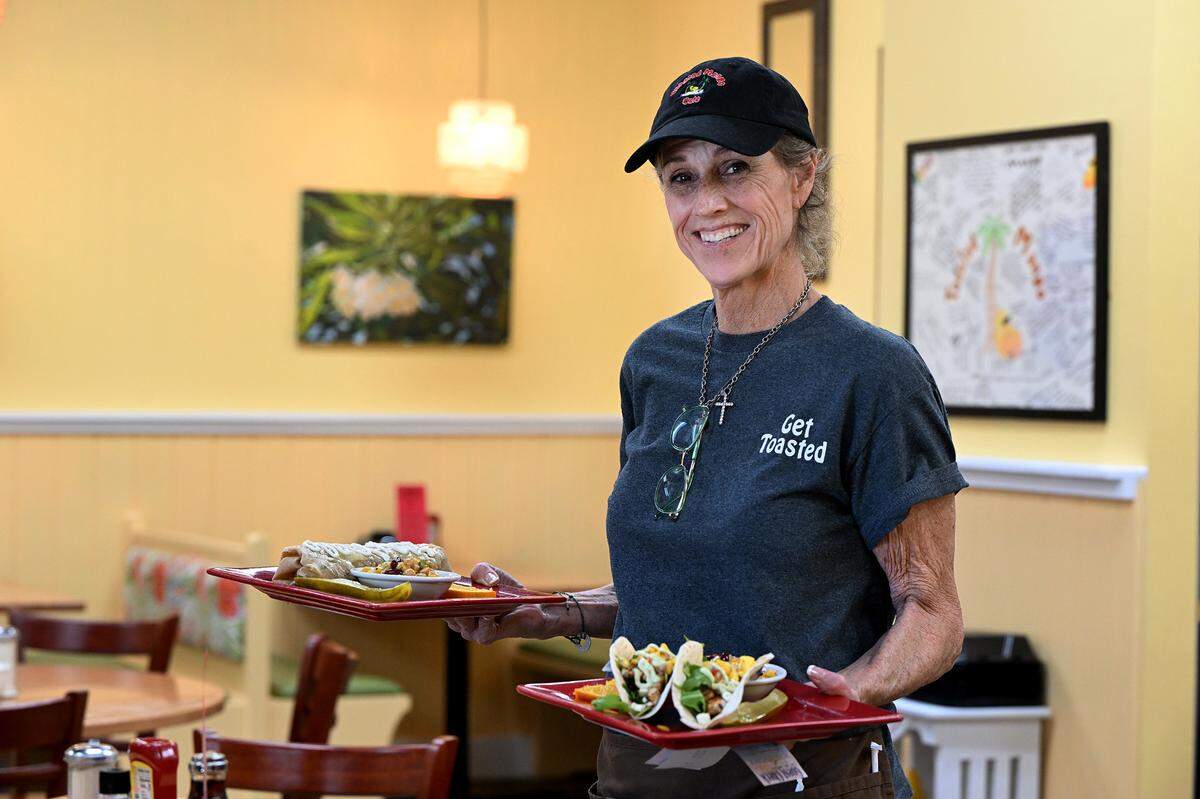 Server Sue Collard brings out an order at the Toasted Mango Cafe in Holmes Beach.