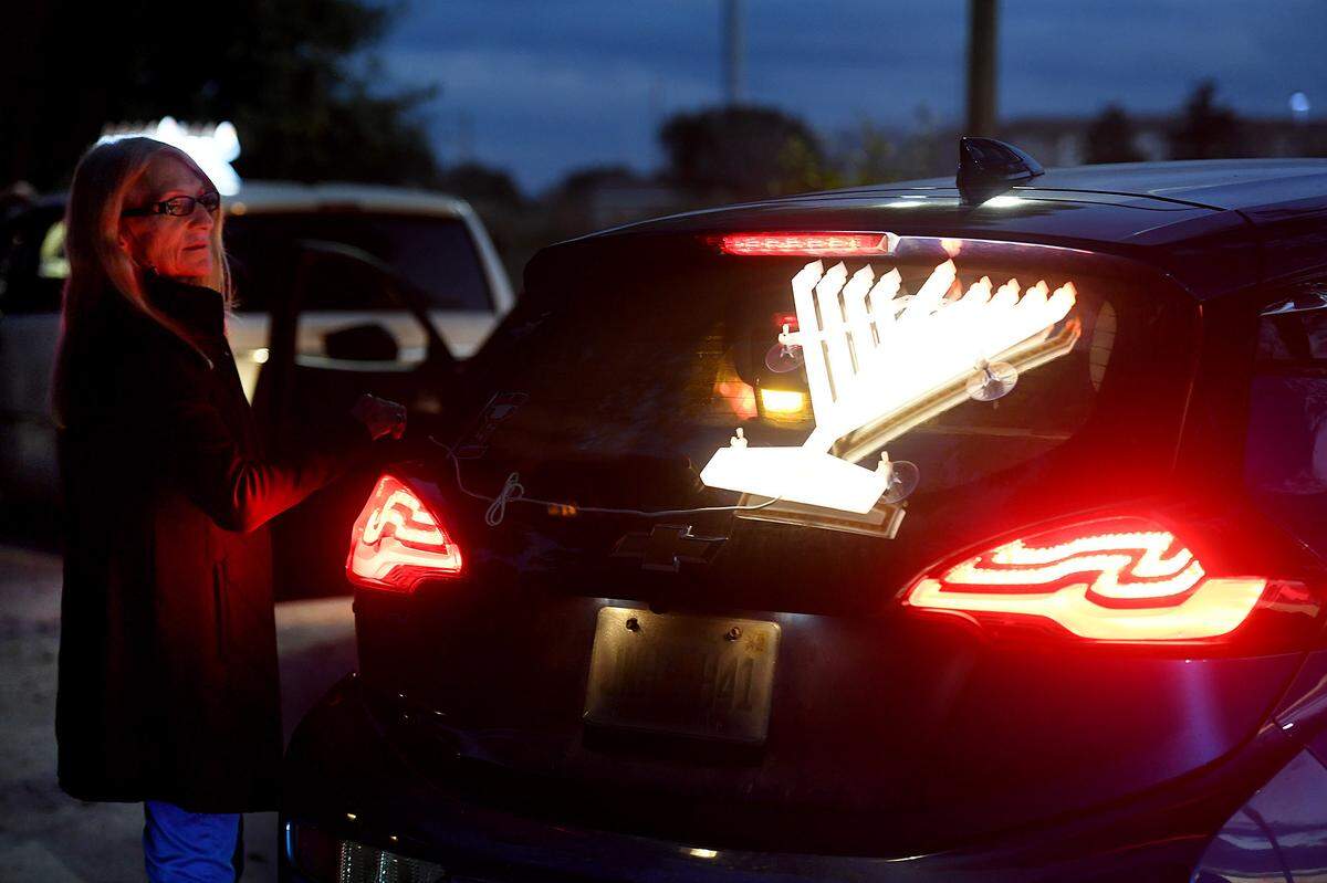 12/01/21—A member of the Chabad of Bradenton checks a lit menorah on the back of one of the cars as they celebrated the 4th night of Hanukkah.