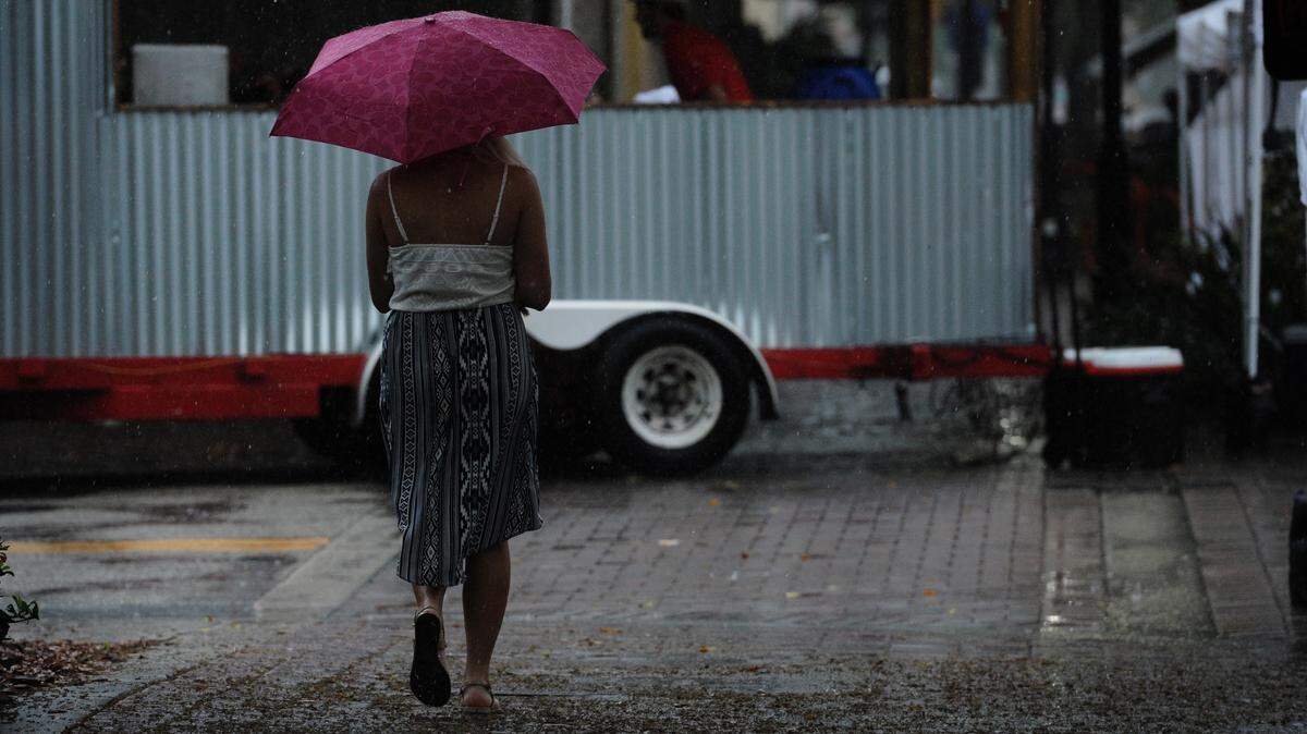 A woman walks in the rain at the Bradenton Farmers Market as a front brings storms to the area Saturday. 
 GRANT JEFFERIES/Bradenton Herald