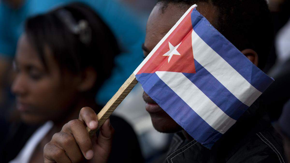 A Cuban fan uses a paper flag to shield his face from the sun during a baseball game between the Tampa Bay Rays and the Cuban national baseball team, in Havana, Cuba, Tuesday, March 22, 2016. Tampa Bay defeated the Cuban team 4-1 at a game attended by President Barack Obama and Cuba's President Raul Castro. (AP Photo/Rebecca Blackwell)