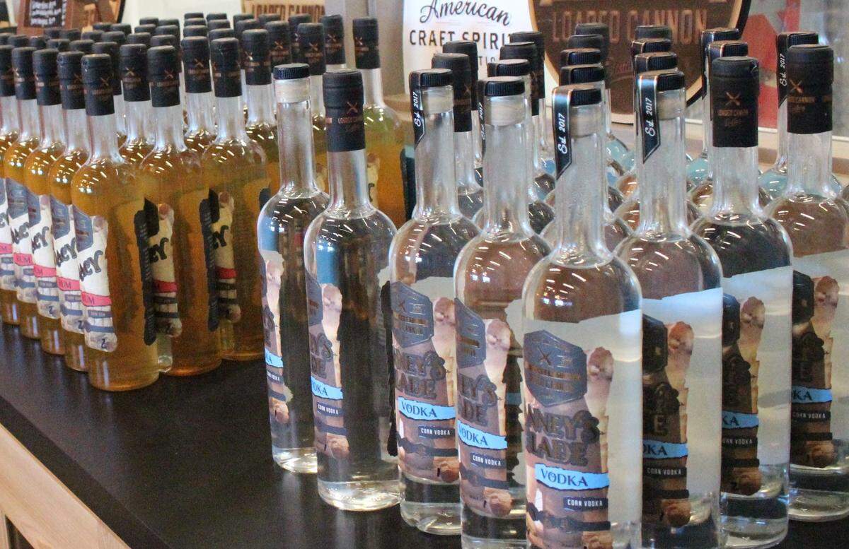 Bottles of Loaded Cannon Distillery vodka and rum are lined up behind the bar of the tasting room.