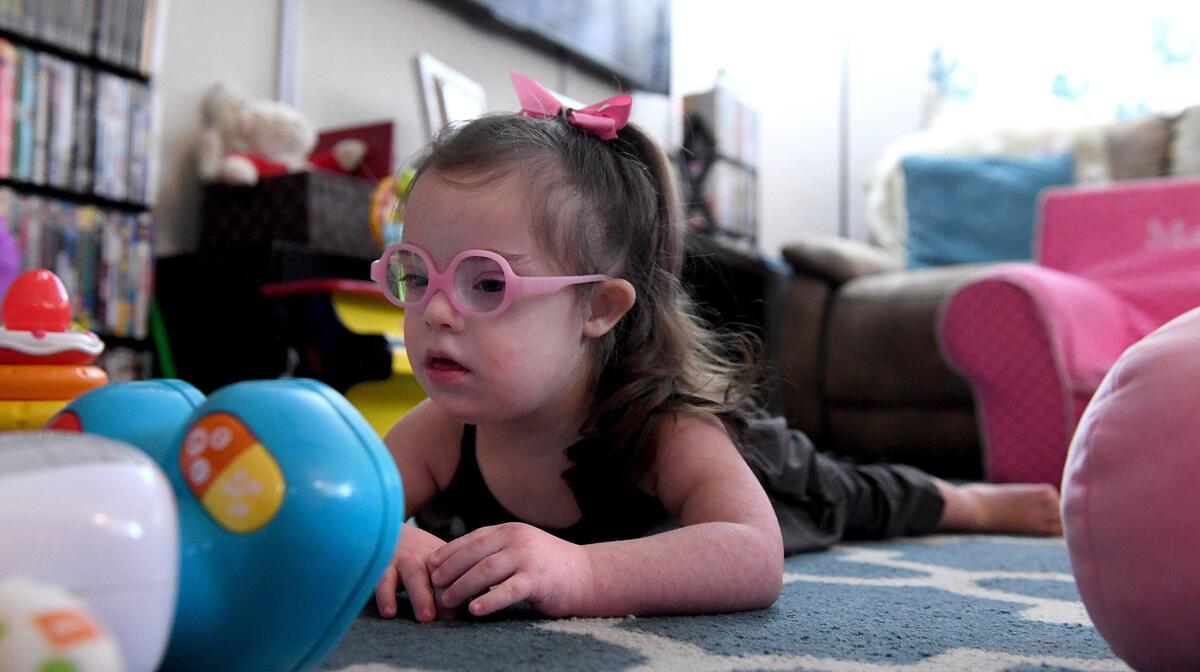 Maddie Gordon, 2, plays with her favorite toys in her living room, pink bow holding a curled ponytail that bounces as she moves. Maddie’s pediatric therapy program at Blake Medical will soon be moving to Manatee Memorial Hospital.