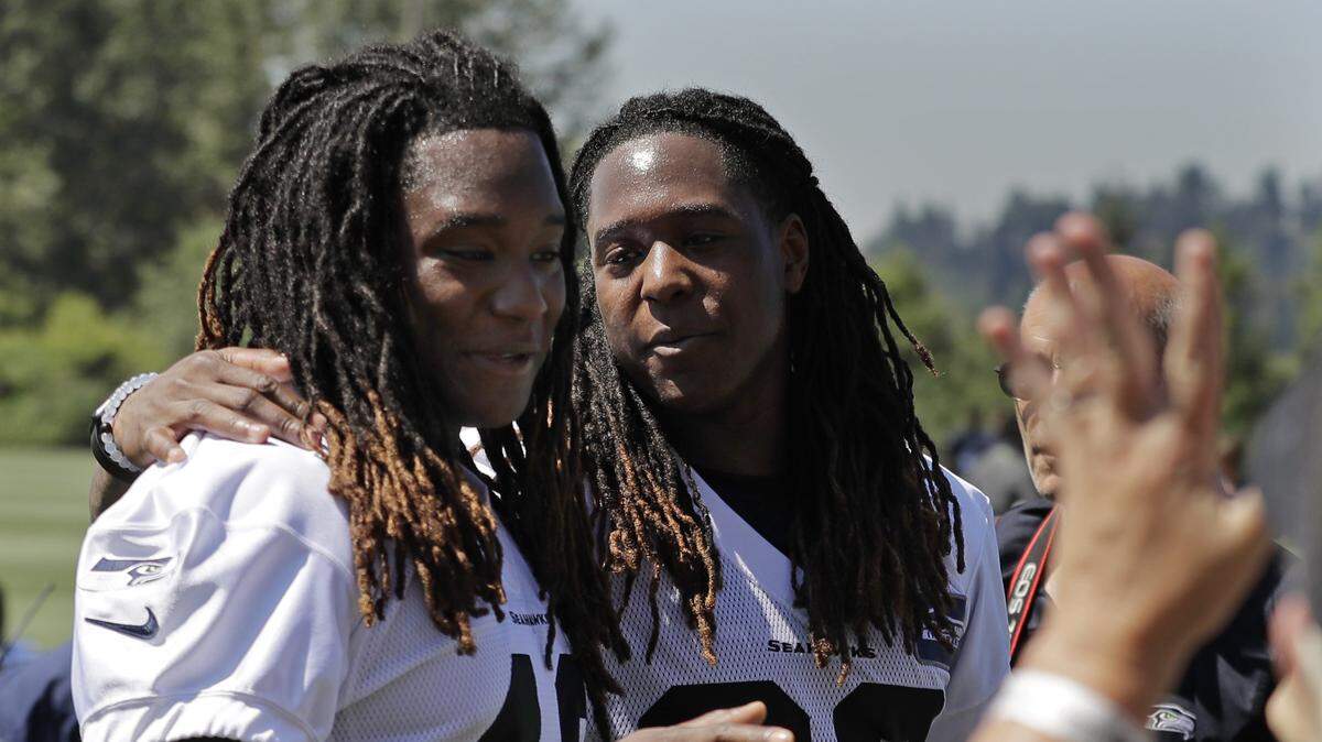 Seattle Seahawks’ twin brothers, linebacker Shaquem Griffin, left, and cornerback Shaquill Griffin, greet fans after NFL football training camp, Thursday, July 26, 2018, in Renton, Wash.