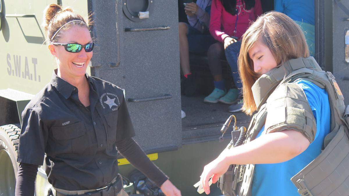 SWAT medic Amy Kemp, the only female deputy in the unit, helps a Girl Scout into a protective vest during a demo and tour of an armored vehicle during Saturday’s career exploration day with the Manatee County Sheriff’s Office.