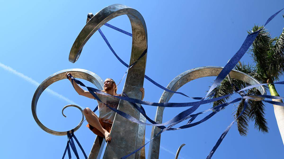 Nick Beck, an environmental studies student, climbs the Four Winds statue in front of the Cook Library at New College as students participated in a one-hour walkout to protest DeSantis’ recent education-related policies.