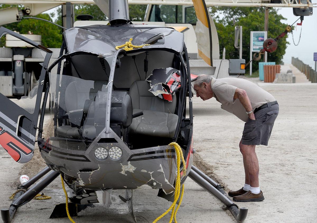 A curious onlooker peers into a helicopter that crashed into the Gulf of Mexico and was pulled from the waters by Sea Tow, then loaded onto a flat bed truck at Coquina Boat ramp for transportation to a secure facility.
