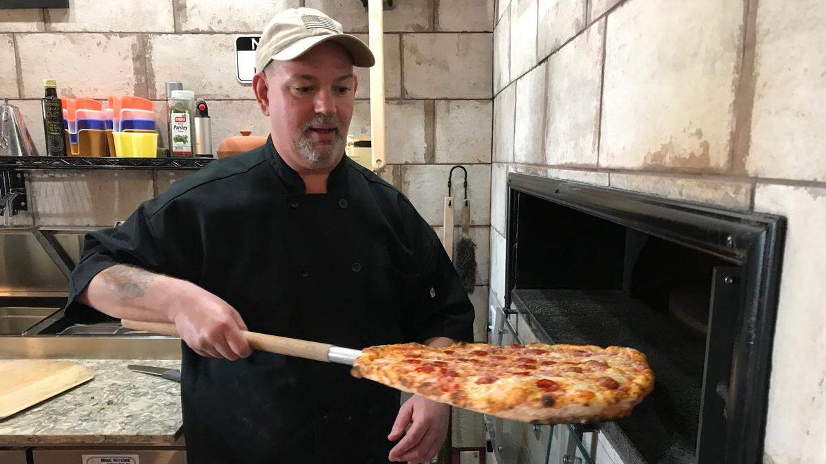 1/1/2019--Alex Christianson pulls a pizza out of the brick oven at Brancato’s, 5227 Manatee Ave. W., Bradenton, in this file photo from two years ago..
