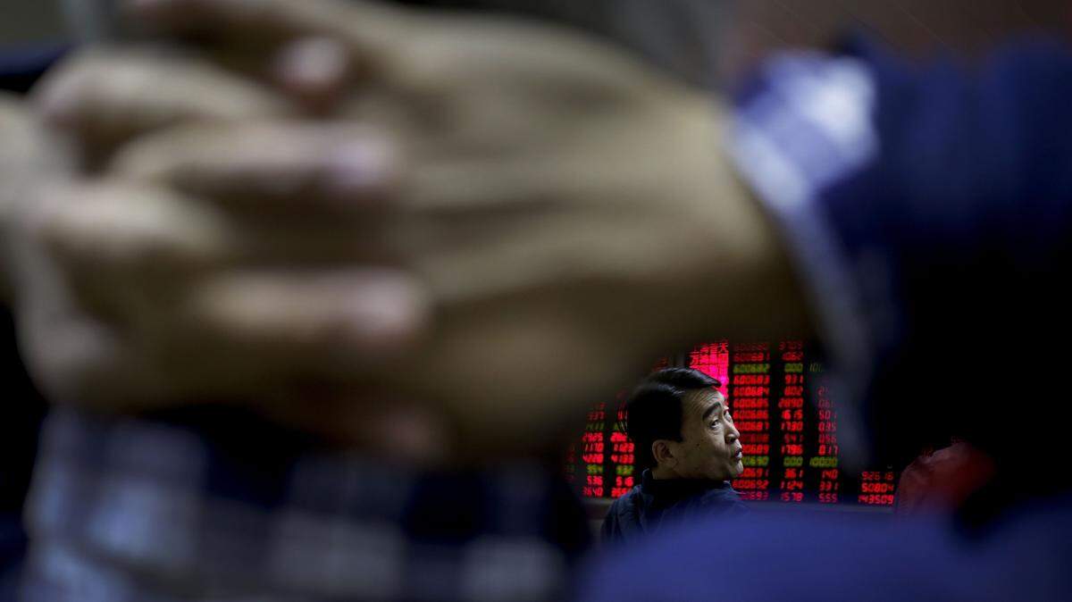 A man chats with other investors near an electronic board displaying stock prices at a brokerage house in Beijing, Tuesday, Jan. 19, 2016. Chinese shares were buoyed but the rest of Asian stock markets were largely flat Tuesday after China's quarterly economic growth met expectations, calming some of the investor jitters in the region. (AP Photo/Andy Wong)