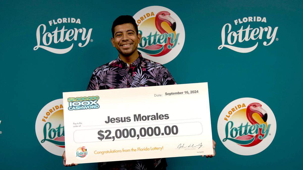 Jesus Morales poses with an oversized check after claiming a $2 million top prize from the $2,000,000 100X CASHWORD Scratch-Off game at Florida Lottery Headquarters in Tallahassee.