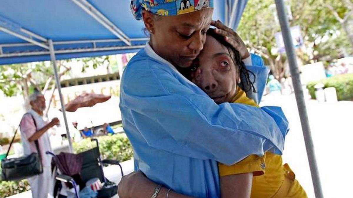 Jackson Health System employee Nancy Spain hugs Marlie Casseus, a Haitian woman who had a 16-pound tumor removed from her face at Jackson Memorial Hospital in 2005, as she visits Jackson to say thanks Thursday. Spain remembers meeting Marlie when she was at the hospital for her surgery. 
 PATRICK FARRELL/pfarrell@miamiherald.com