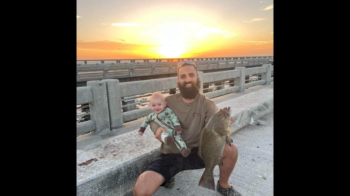 Jacob Crue and his 7-month-old son, Tide, pose with a 25-inch gag grouper caught fishing from the Skyway Bridge Fishing Pier on Sunday, Sept. 3, 2023.