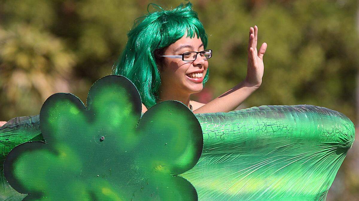 Amaris Monosiet waves from a big green hat while participating in a past St. Patrick’s Day Parade in Village of the Arts.