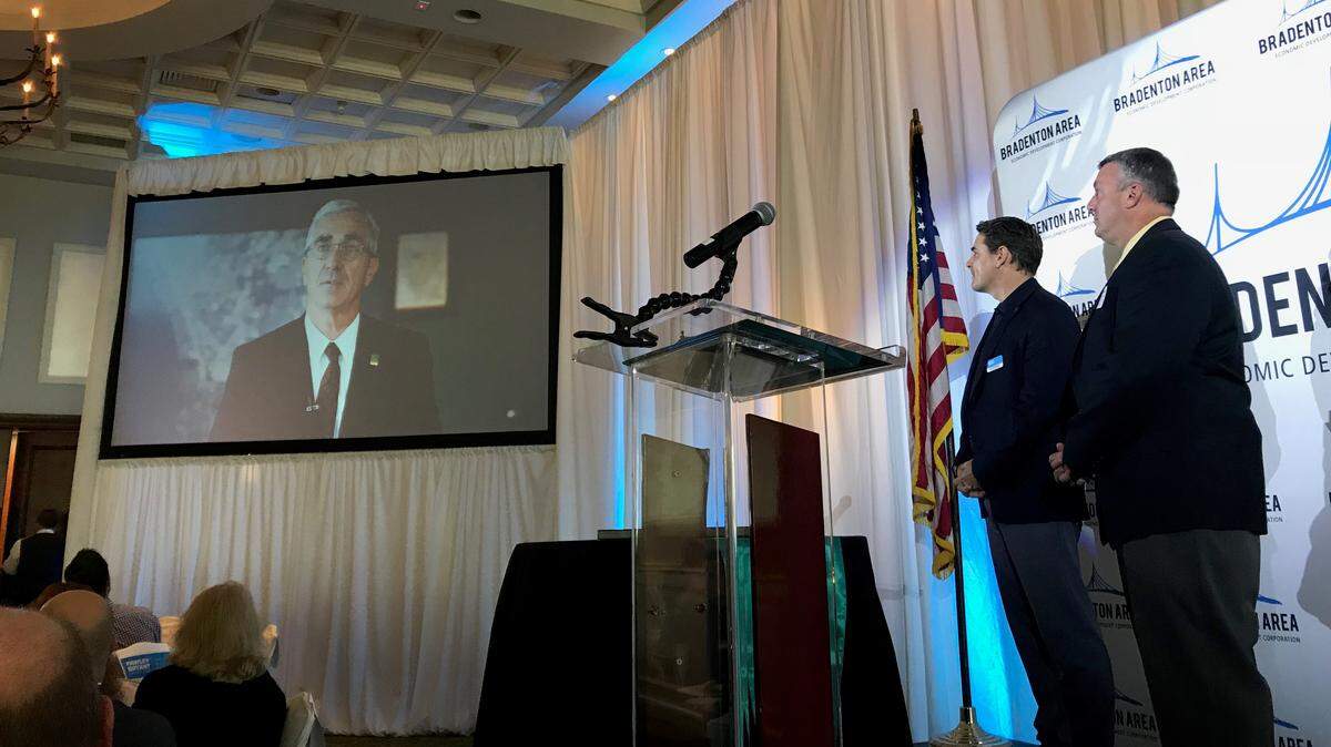 Rick Piccolo, recipient of the Rick Fawley Economic Development Award of Distinction, spoke to the Bradenton Area Economic Development Corporation annual update luncheon by video. Looking on were Stu Henderson and Steve Padgett. Piccolo, CEO and president of Sarasota Bradenton International Airport, was recognized for double digit increases in business at the airport this year.