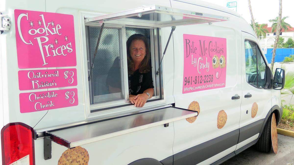 Cindy Unzicker, owner of Bite Me Cookies by Cindy, poses for a photo through the service window of her van, which is decorated with all sorts of cookie-inspired designs. She said she has no plans to move to a brick-and-mortar shop. Instead, she hopes to outfit her van with an oven to start baking her cookies on-the-go.