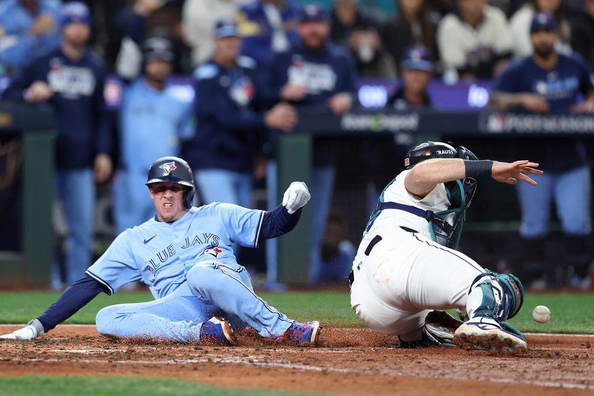 SEATTLE, WASHINGTON - OCTOBER 16: Myles Straw #3 of the Toronto Blue Jays scores a run past Cal Raleigh #29 of the Seattle Mariners during the eighth inning in game four of the American League Championship Series at T-Mobile Park on October 16, 2025 in Seattle, Washington.  (Photo by Steph Chambers/Getty Images)
