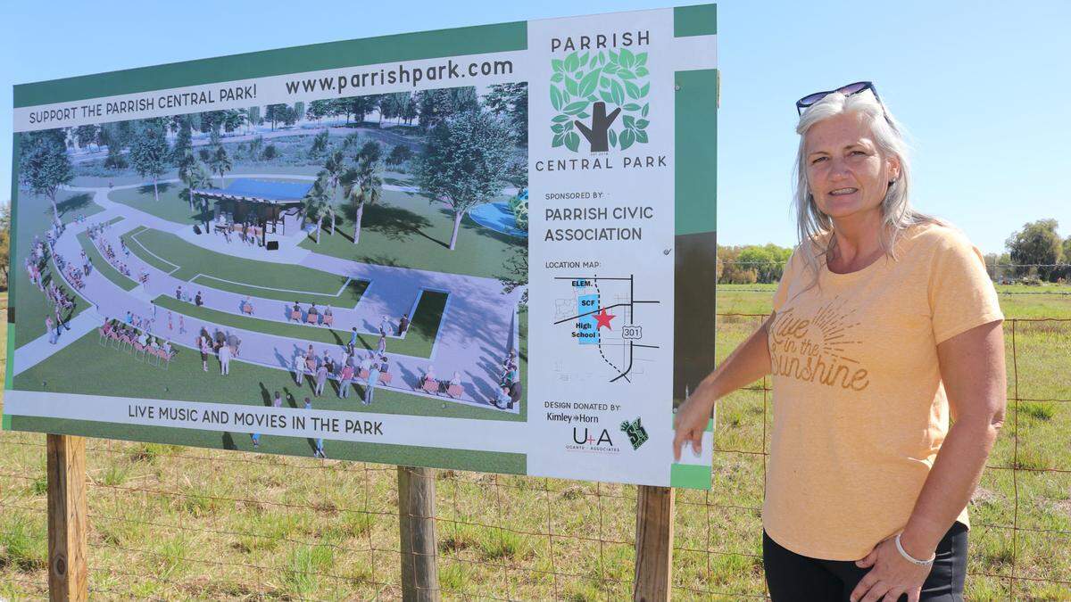 2/25/2021--Gretchen Fowler, president of the Parrish Civic Association, stands next to a sign showing what the proposed Parrish central park could look like.