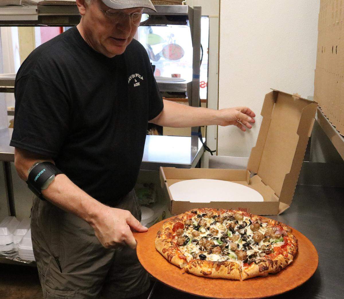Brad Meilink puts a hot-from-the-450-degree oven Raven Deluxe pizza goes into the delivery box this week at Raven Pizza and More, 8255 U.S. Highway 301 N., Parrish.
