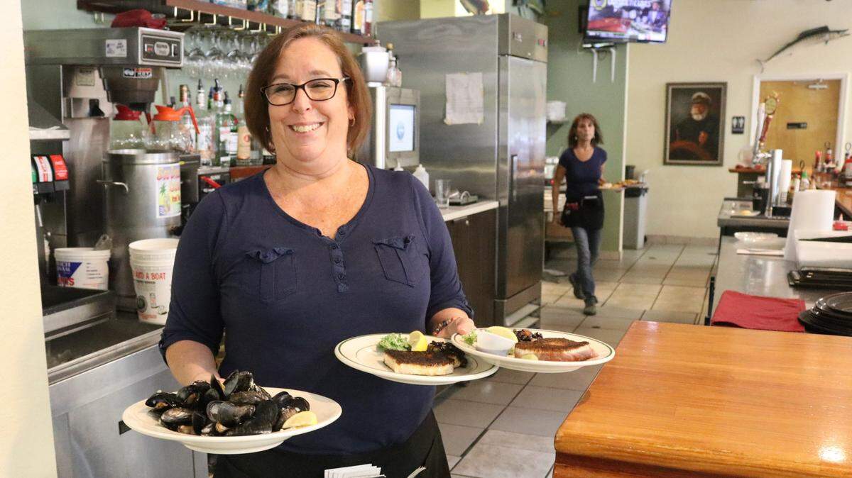 Sarah O’Rouke delivers platters of seafood to guests at Captain Brian’s Seafood Market and Restaurant in Sarasota.