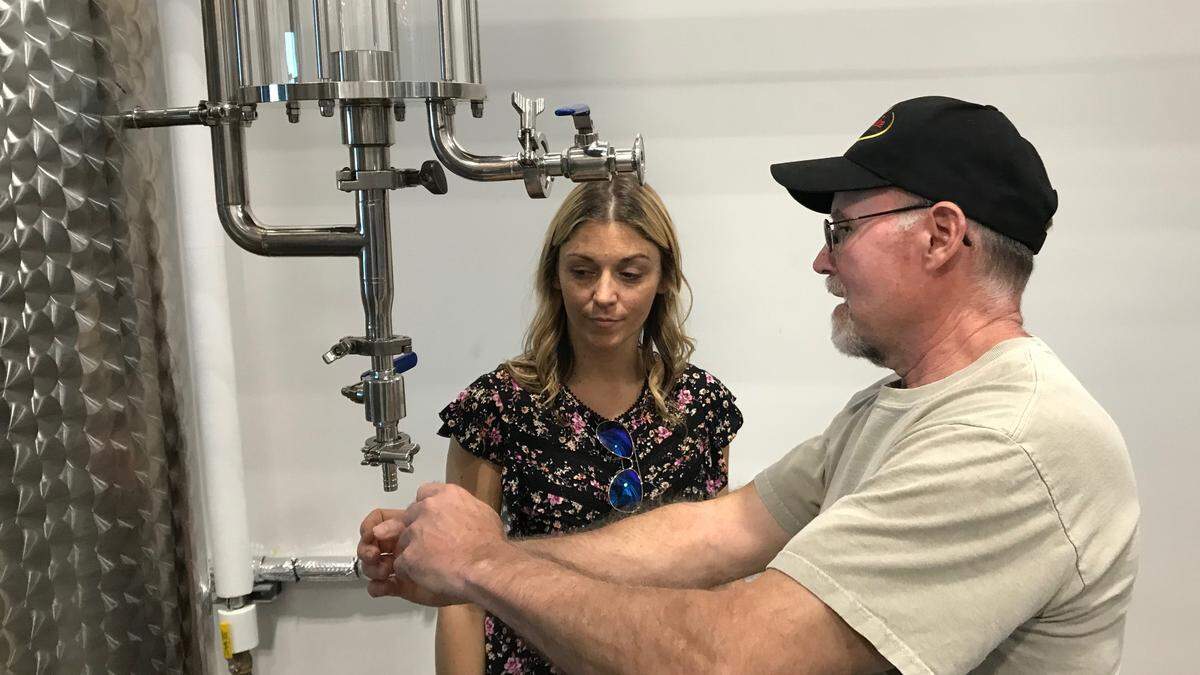 Steve Milligan explains the workings of a piece of distilling apparatus to Michelle Russell at Loaded Cannon Distillery and Tasting Room.