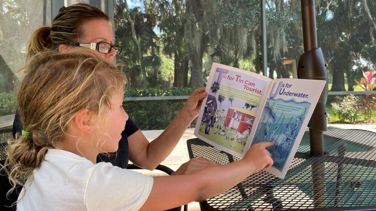 Jodi Carroll reads “Old Manatee A to Z” to her granddaughter, Lillian Kalousek of Lake Forest, Ill. Realize Bradenton recently published the childrens book which is focused on the rich history of East Bradenton.