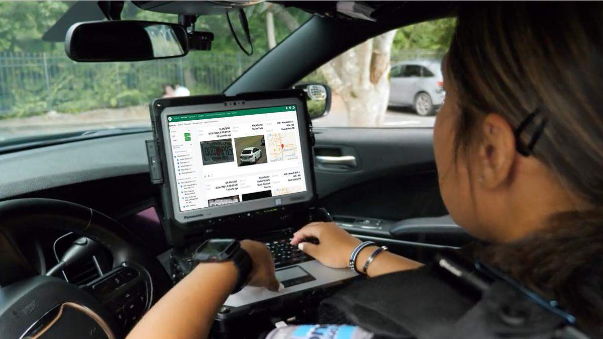 Promotional image from Flock Safety showing a law-enforcement officer using the system from inside a patrol car.