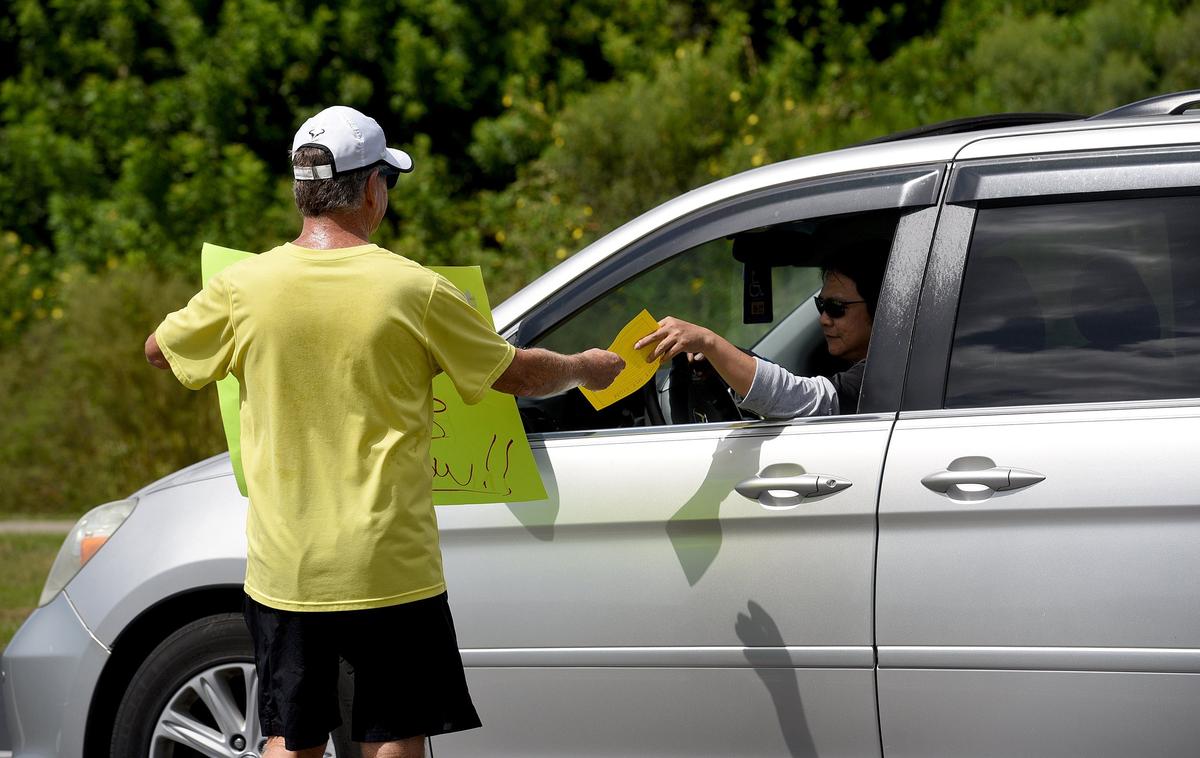 Around 20 people showed up outside Kinnan Elementary School at dismissal time Monday to hand out fliers and hold signs against the construction of a communications tower close by.