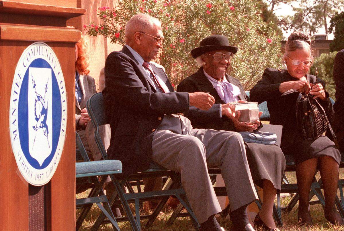 9/9/1999--Ernest Brown reaches for a box of commemorative sand that his mother-in-law, Mary Hall, had just placed in the box during the groundbreaking ceremony of the Heritage House African-American Museum at MCC. Brown and his wife, Fredi, left, have loaned their collection to the college for the education of the community.