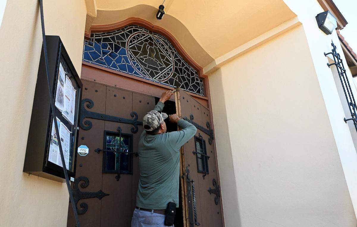 After the rains from Hurricane Ian left the front doors of Bradenton’s Sacred Heart Catholic Church swollen shut, a man works to get them operable on October 3, 2022. Father Elbano Munoz said the congregation is gathering supplies for their sister church in Arcadia, who have many parishioners who lost everything in the storm.