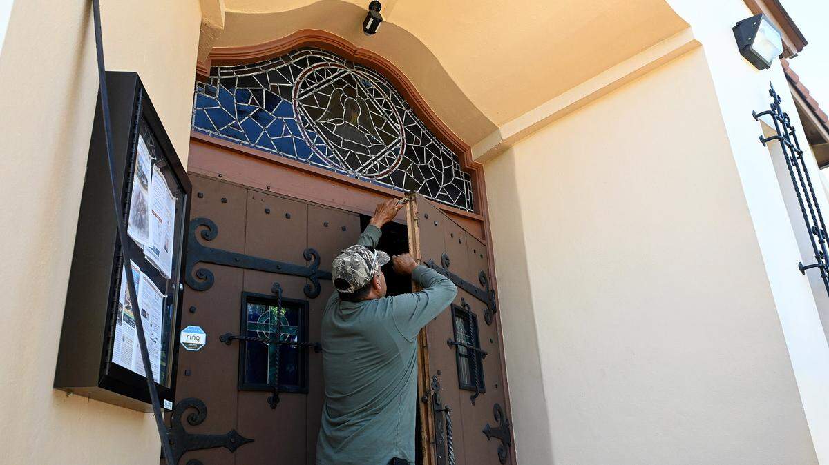 After the rains from Hurricane Ian left the front doors of Bradenton’s Sacred Heart Catholic Church swollen shut, a man works to get them operable on October 3, 2022. Father Elbano Munoz said the congregation is gathering supplies for their sister church in Arcadia, who have many parishioners who lost everything in the storm.
