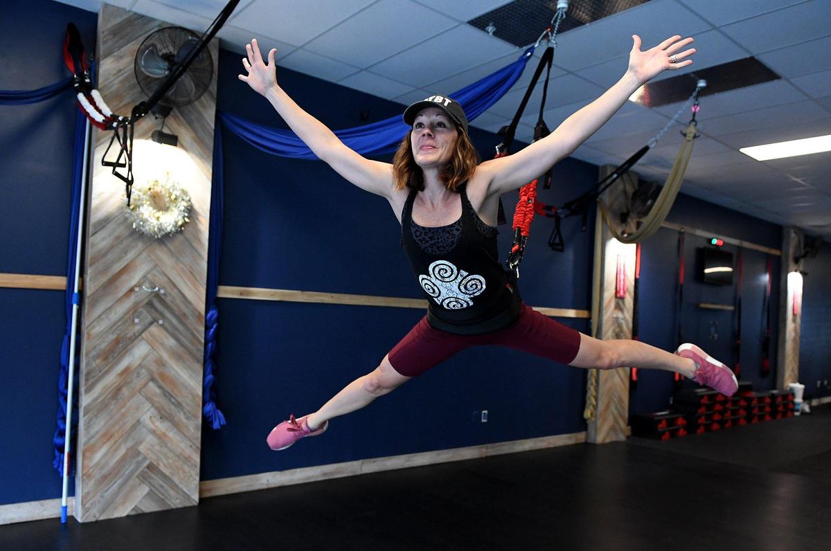 Jessica Currin, owner of One Tribe Fitness in downtown Bradenton, demonstrates exercises in a bungee harness.