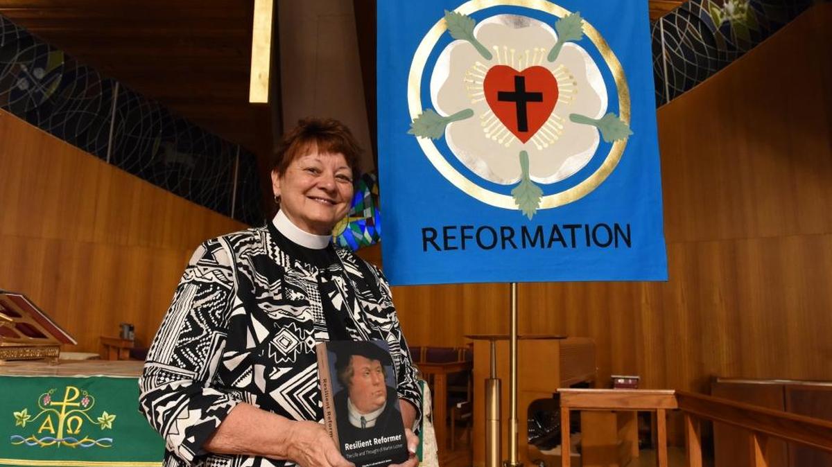 Pastor Rosemary Backer, of Gloria Dei Lutheran Church, stands in front of a Reformation banner Wednesday. The church will be holding several Martin Luther-themed events in October.