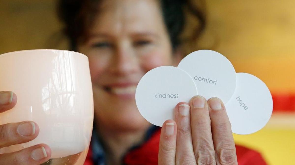 Lee Rhodes, owner of Glassybaby, holds one of her votive candle holders and several cards used for individual descriptions of each holder made there, including “kindness,” “comfort” and “hope,” in her shop in Seattle. Rhodes says that she has seen her products with the positive labels surge past holiday themes like “elf” and “joy” since Election Day.