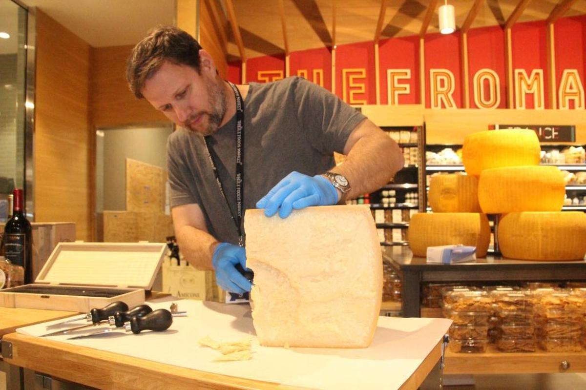 A staff member shaves a bit of Parmesan-Reggiano cheese in 2018 at the Whole Foods Market at 5298 University Parkway.