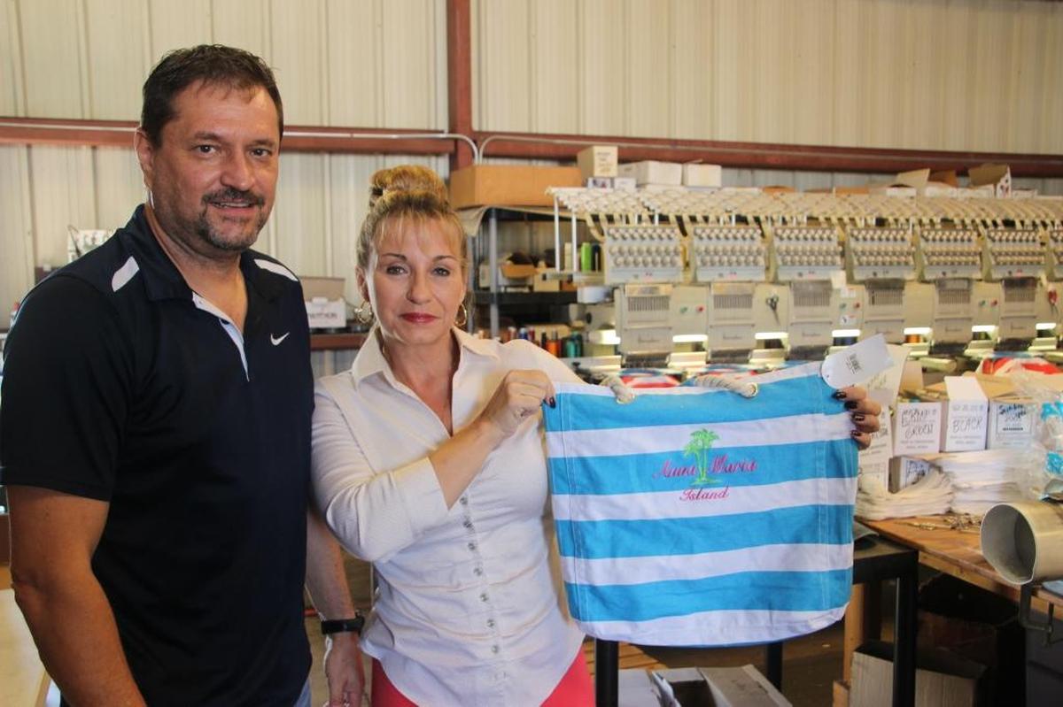 Tom and Stacey Carollo display one of their embroidered tot bags made for the local resort community. Their company, Windy City Apparel, is located at 2331 A Whitfield Industrial Way in southern Manatee County.