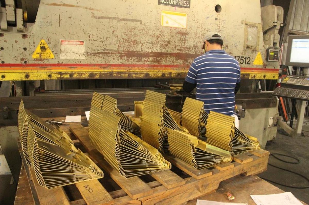 A worker stamps out brass components for engine oil reservoirs at Edmunds Metal Works. The company manufactures a wide variety of products.