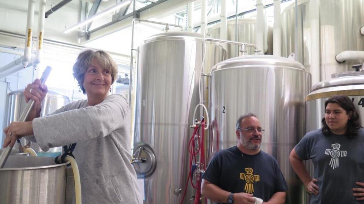 Valerie Fisher, Prism Youth Initiative board president, stirs grain with water at Darwin Brewing Co. with the help of lead Darwin Brewing Co. brewer Jorge Rosabal and brewer Antonio Hernandez. Eventually, the starches turn into fermentable sugar that will become the Manatee Pride beer, exclusive to the Manatee Pride Festival.